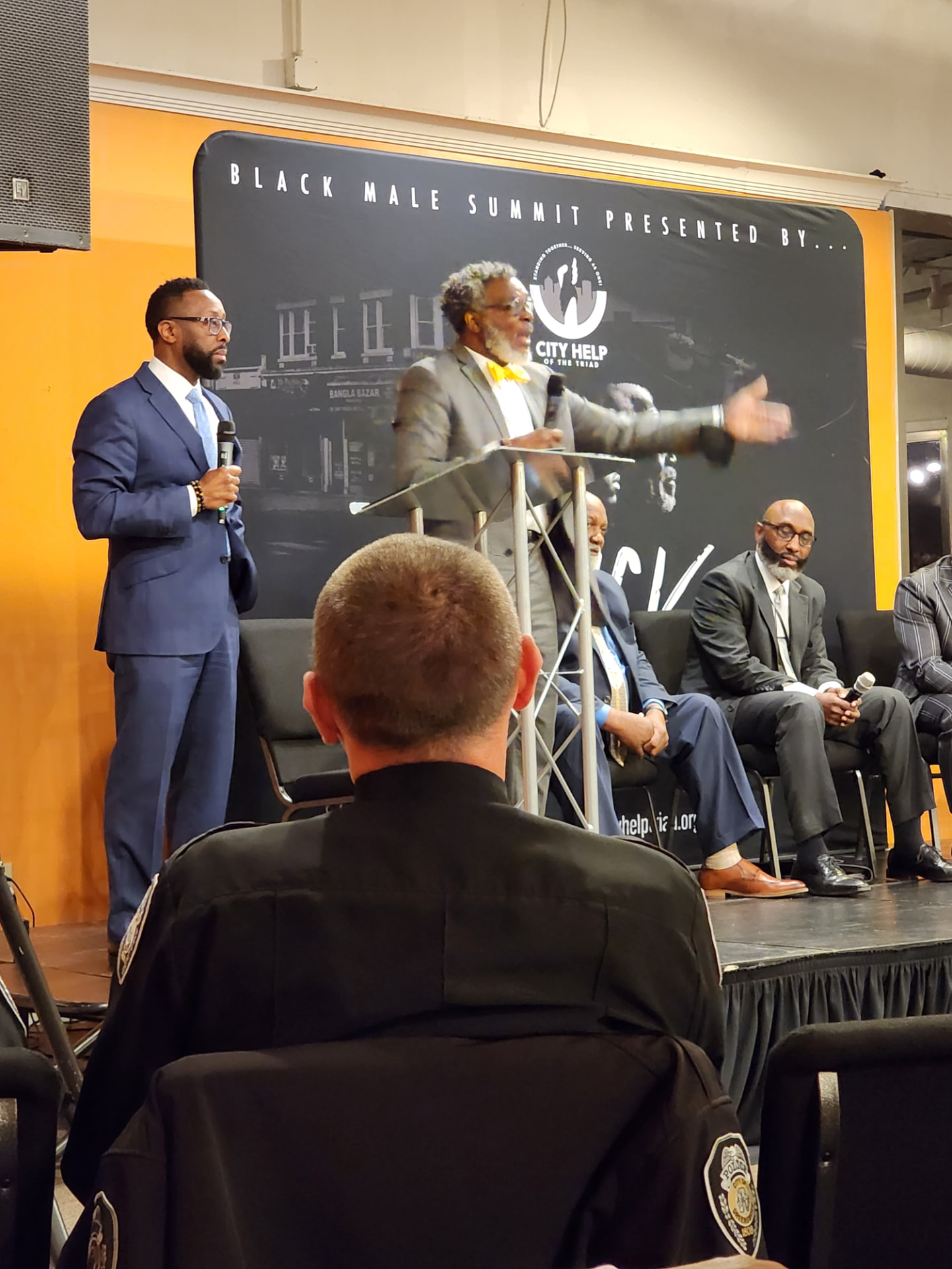 A speaker addressing the room from the podium in front of the Black Male Summit banner
